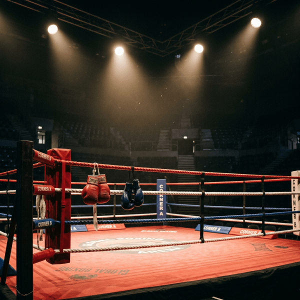 Empty boxing ring with red and blue boxing gloves hanging in corner